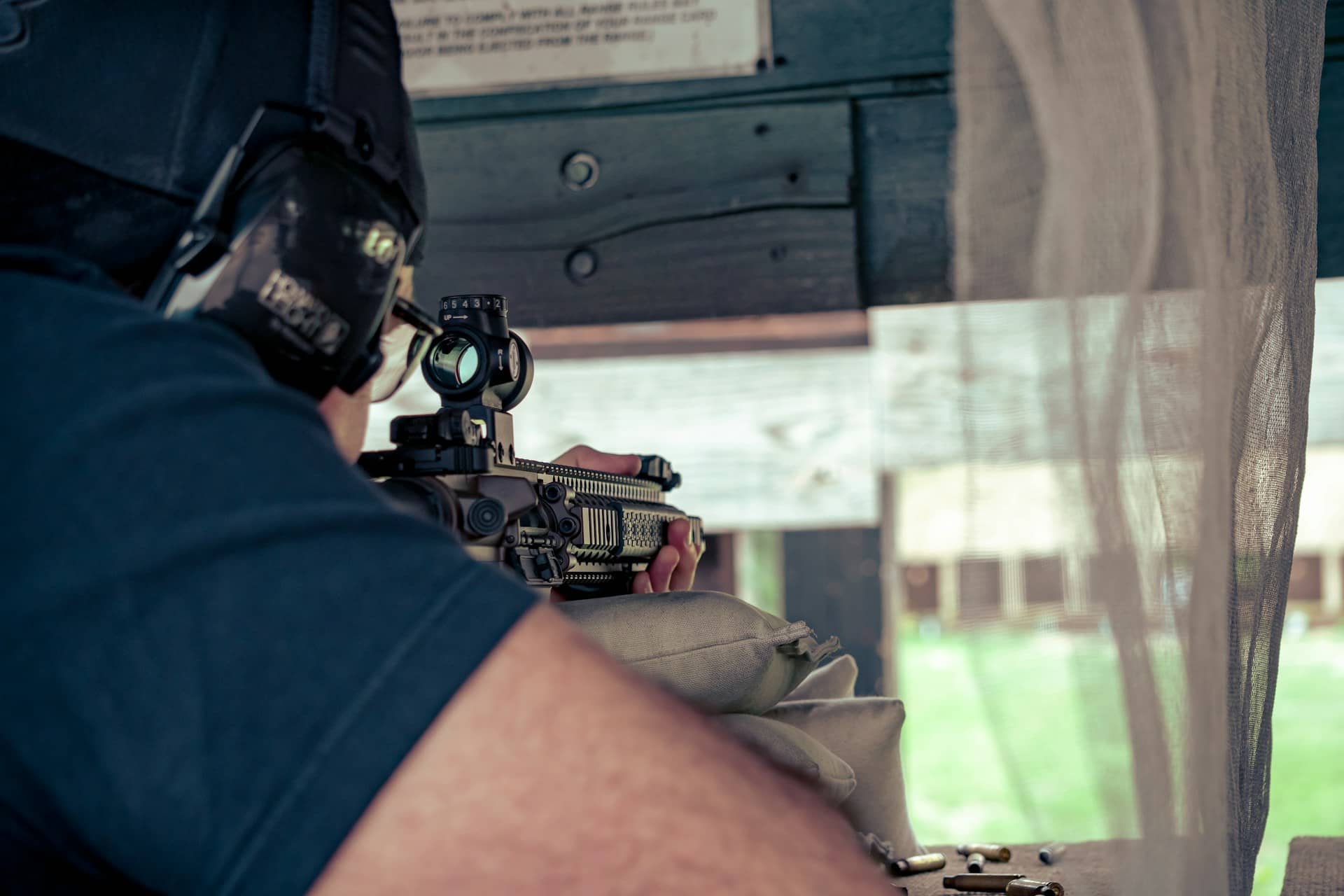 Man aiming a rifle with an optic