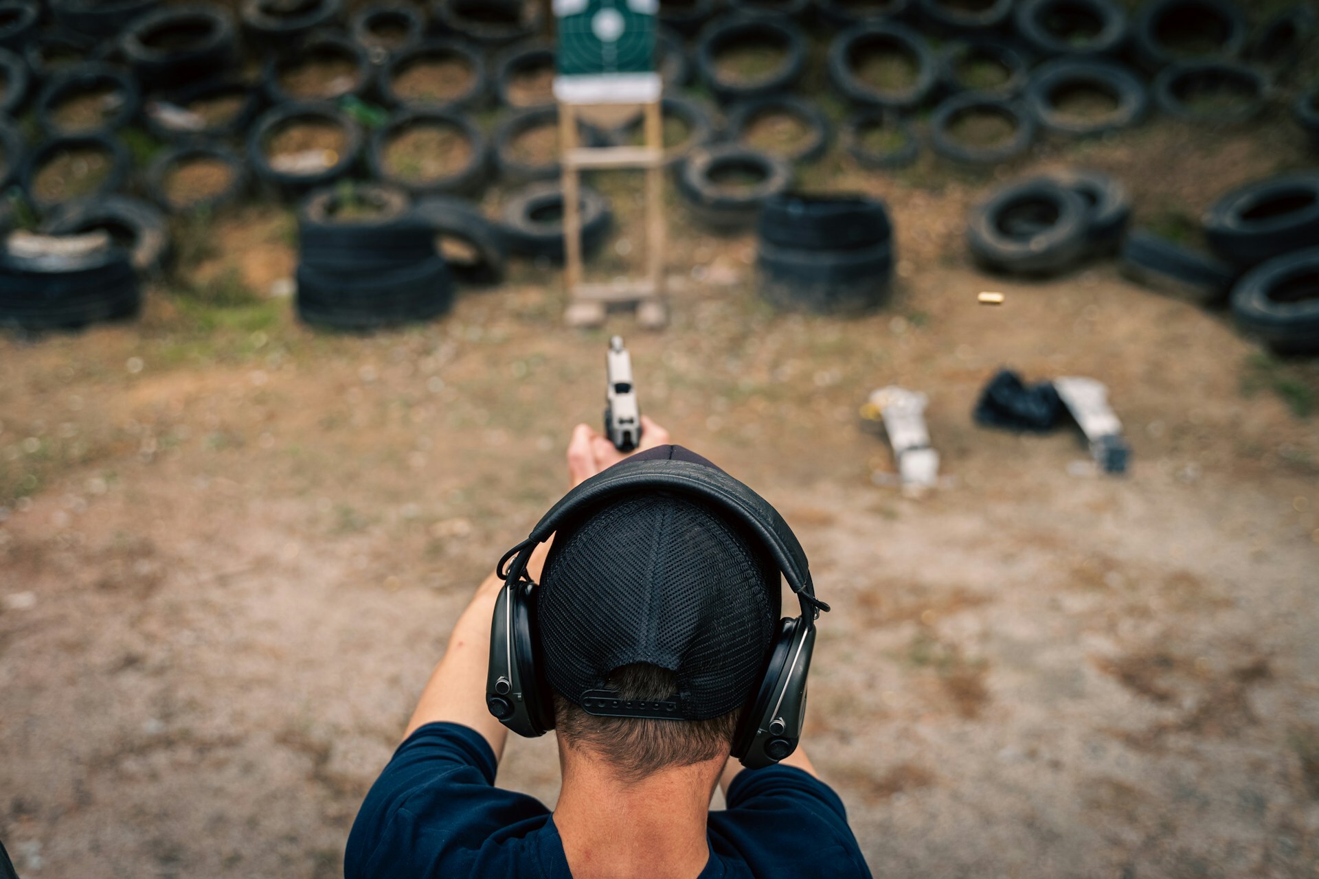 Man with ear protection firing at target
