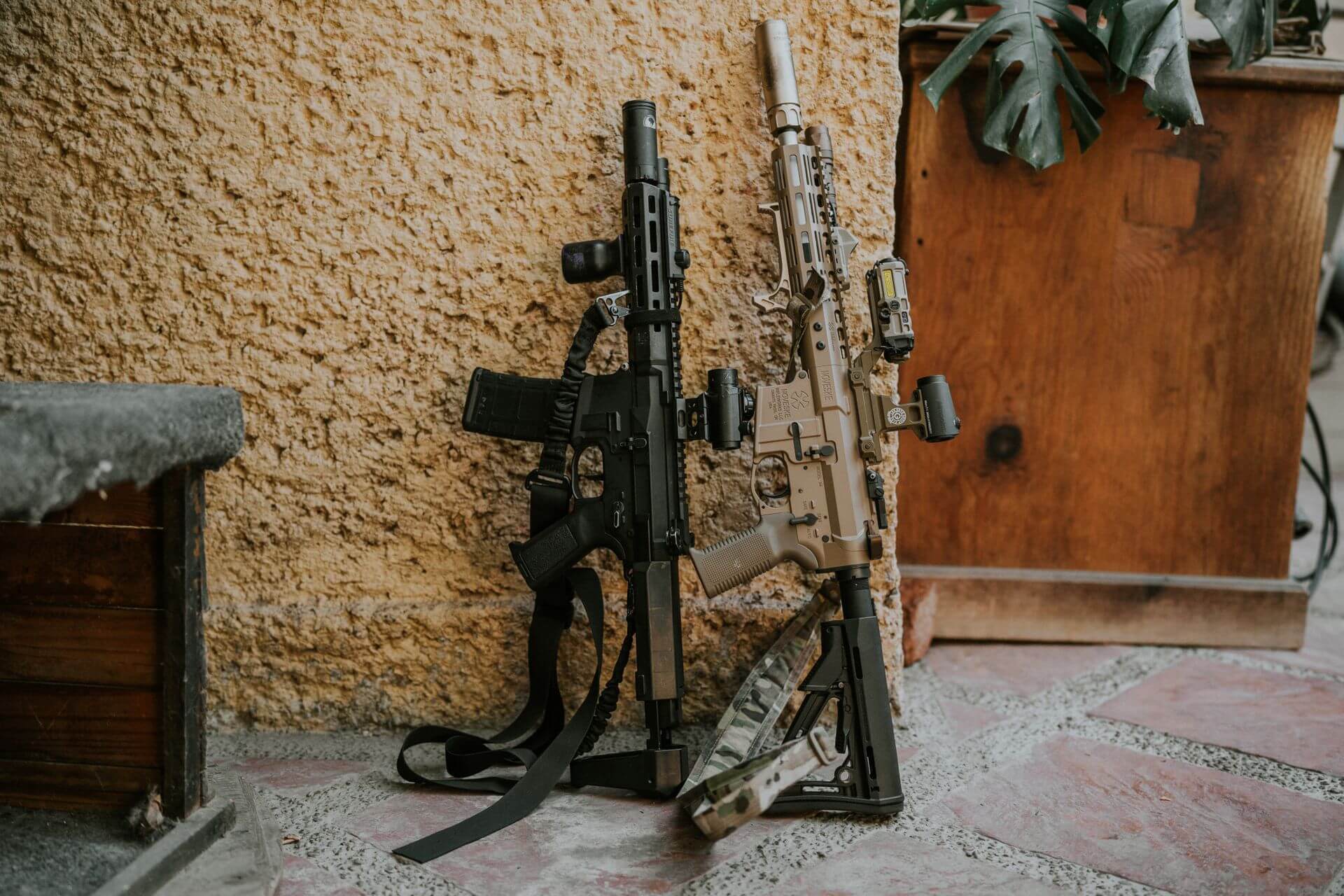 Two suppressed rifles leaned against wall